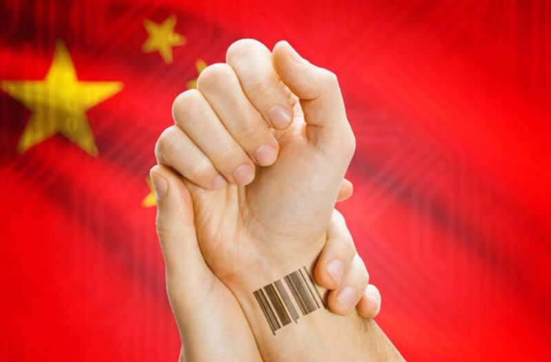 Hand with a barcode on its wrist, held by another hand, with China’s flag in the background