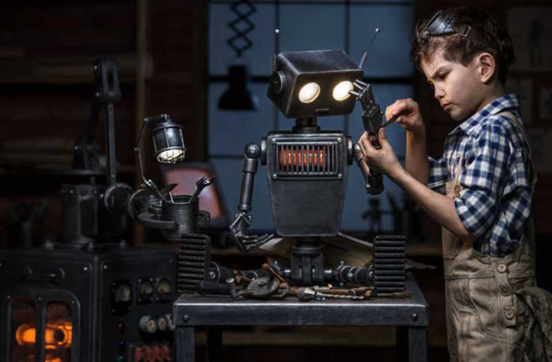 Young boy fixing a robot in his workshop