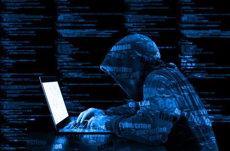 A hacker in a hoodie typing on a laptop, with lines of code in the background