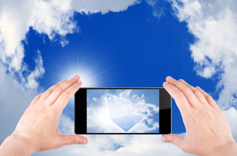 Hands holding a smartphone and taking a picture of a blue sky with clouds