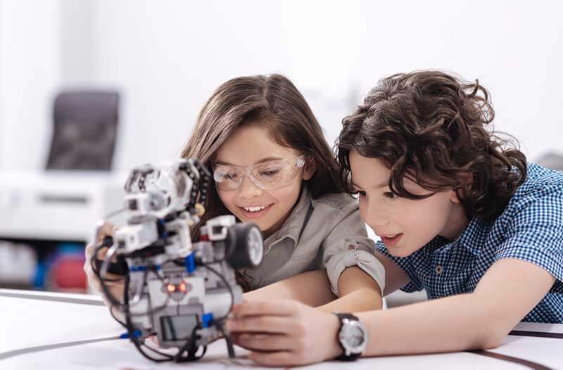 Two kids interacting with a robotic device