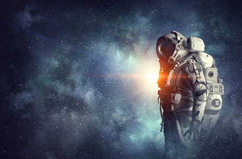 Man wearing an astronaut suit standing in space with a lot of stars in the background