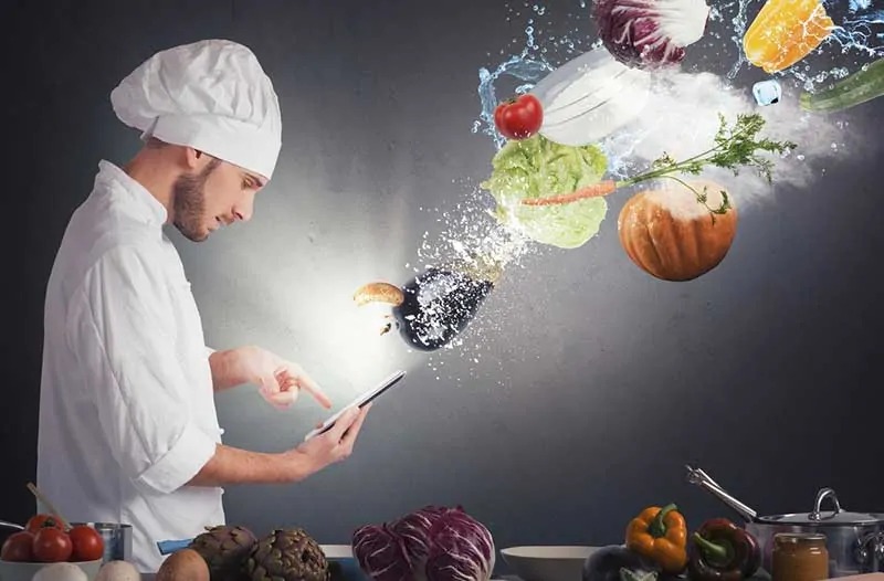 Chef-kok met een smartphone in zijn hand waarboven allerlei soorten groenten zweven