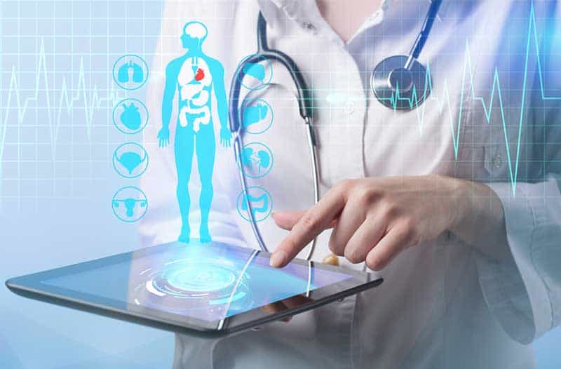 Lady in white lab coat holding a tablet with a digital image of a person and health-icons floating above it