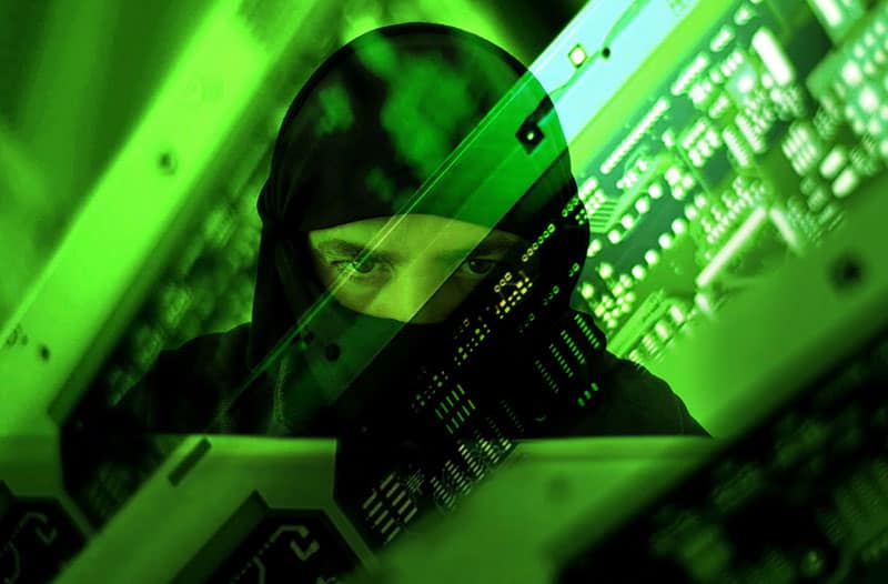 Green computer screen with a reflection of a man in a black hoodie