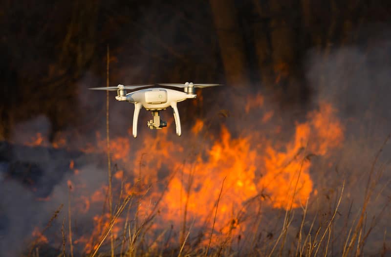 A drone flying over grass that’s on fire