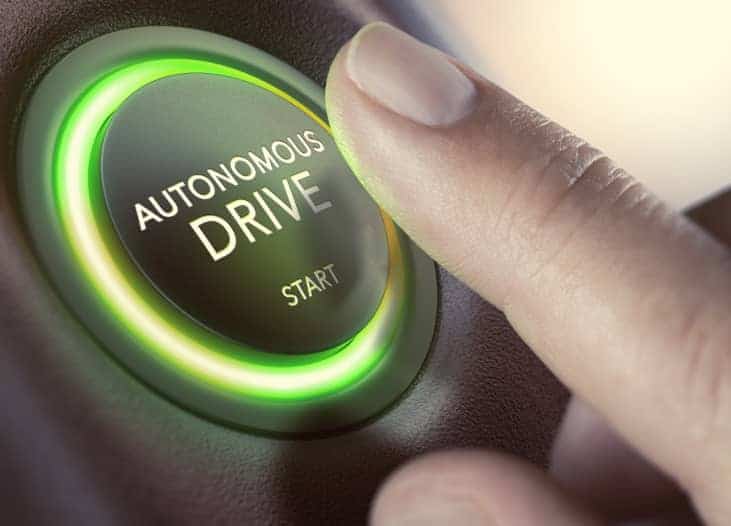 Finger pushes on round button with the text ‘autonomous drive’