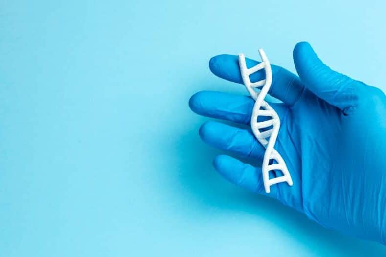 Hand in blue glove holding a DNA-strain